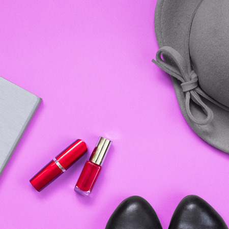 Pair of black shoes grey notebook  and grey lady falt hat  with bowknot on edges  and bright red lipstick and nail polish in the middle of pastel pink square background. Top view.の写真素材