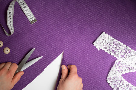 Horizontal piece of ultraviolet cloth, with measuring tape, buttons, human hands with cutting-out...