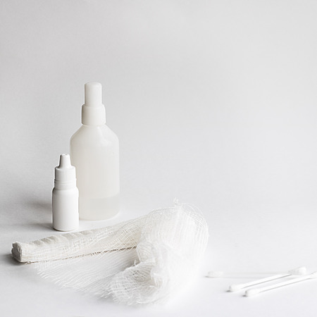 two white medicine bottles big and little, roller bandage and three cotton buds on the white background Square shot with copy spaceの写真素材