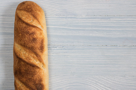One loaf of french homemade brown and orange bright baguette bread put vertically on left part...