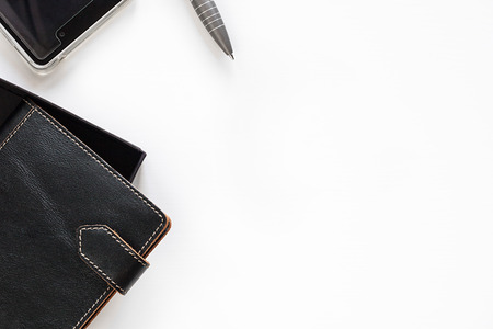 Leather closed two notebooks with clips with orange stitch on edges half seen put diagonally and edge of grey pen, mobile phone on the left side on of horizontal shot on the empty white background for copy space top viewの写真素材