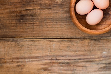 Eggs in wooden bowl on brown wooden old textured background. Easter background with copy space for textの写真素材