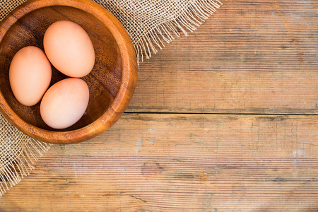 Eggs in wooden bowl on wooden brown old textured background. Easter background with copy space for textの写真素材