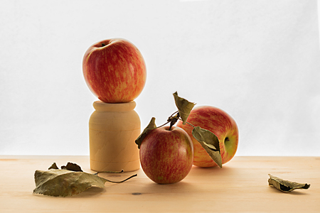 three red apple on wooden table with dry leaveson the white backgroundの写真素材
