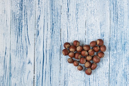 heart made up from hazel nuts on the background of Old and grunge white and blue wooden backgroundの写真素材