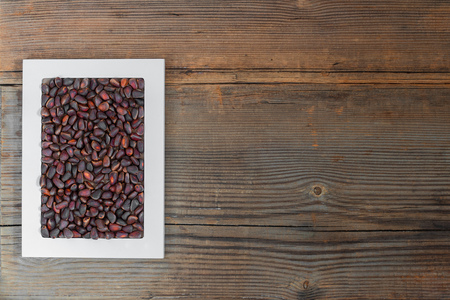 Pine nuts in shells in white frame on old wooden background. Top view with copy spaceの写真素材