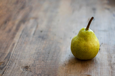 one fresh ripe organic yellow pear on rustic wooden brown table with defocused pears on background. Selective focus. Horizontal with copy space. For design about agricilture, frui, healthy foodの写真素材