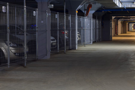 Poorly illuminated parking garage, interior with few parked cars.