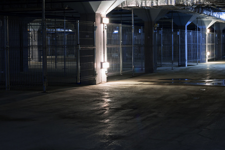 empty poorly illuminated coridor in underground parking garage with separate boxes, Horror