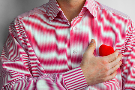 Man weared red striped shirt with his hand on the bright red heart in pocket, Close up, Horizontalの写真素材