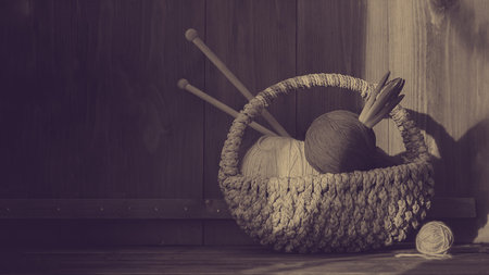 bright yarn with hyacinth in small basket with kniting sticks on old wooden background. Vintage....
