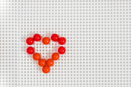 Heart made up with red pins on the white sufrace with grey dots with copy spaceの写真素材