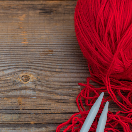 knitting sticks snd red yarn on old textured wooden table. Squareの写真素材