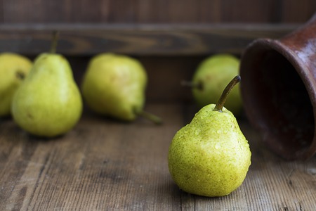 one fresh ripe organic yellow pear on rustic wooden brown table with defocused pears on background. Selective focus. Horizontal with copy space. For design about agricilture, fruit, healthy foodの写真素材