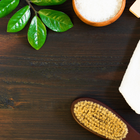 woman body, skincare, massage and bath products, sea salt in bowl, white towel, green leaves, cacus brush for dry massage on black wooden background. Beauty blogger cosmetics Copy space Squareの写真素材