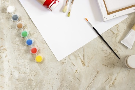 Flatlay with bright paints in small round containers and many palettes, canvas, brush and white sheet of paper on grey cement backcground, Workspace, Mess, drawing, Hobby, Art, creativeの写真素材