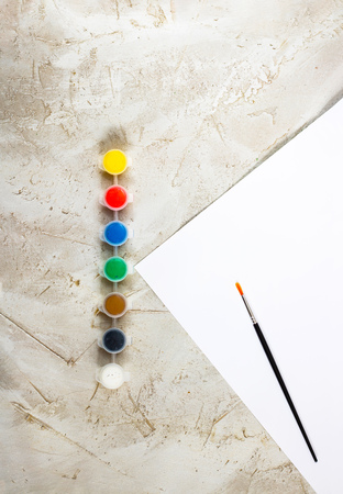 Flatlay with bright paints in small round containers, brush and white sheet of paper on grey cement backcground, Workspace, Artist, drawing, Hobby, Art, minimal, verticalの写真素材
