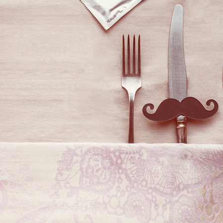 Vintage knife with black moustache and fork on bage table cloth, as man and woman in bed, condom...