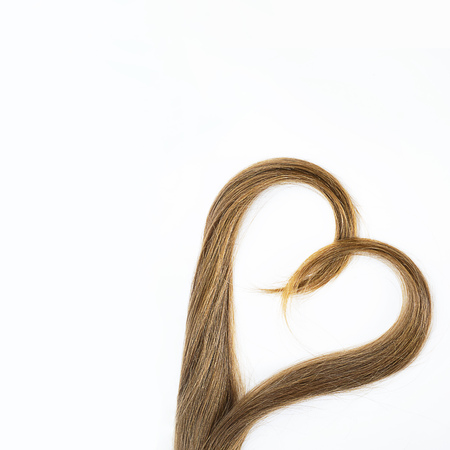 long blond hair donation put like heart for cancer patient on white background. Top view. Natural material for making wig. Square, isolated, copy space. Symbol of kindness and support. Conceptの写真素材