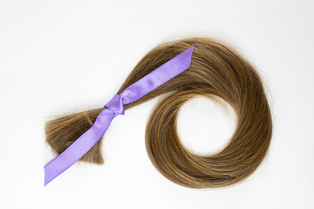 long blond hair donation with lavender ribbon as symbol of fight against cancer on white background. Top view. Natural material for making wig for patients. Concept, Square with copy space, isolated.の写真素材