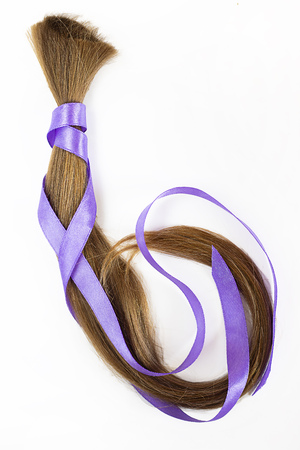 long blond hair donationwith lavender ribbon as symbol of fight against cancer on white background. Top view. Natural material for making wig for patients. Vertical, isolated.の写真素材