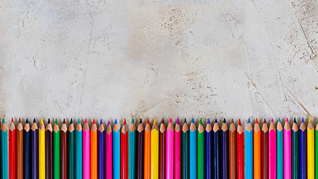 Many bright color pencils on cement grey background, banner with copy space in the middleの写真素材