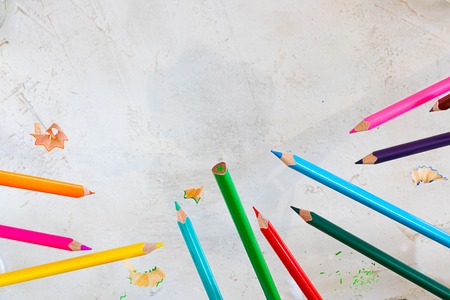 Flying pecils of different colors and bright shavers on the cement grey background, square shot with copy space for text and design, wallpaper for art and educationの写真素材