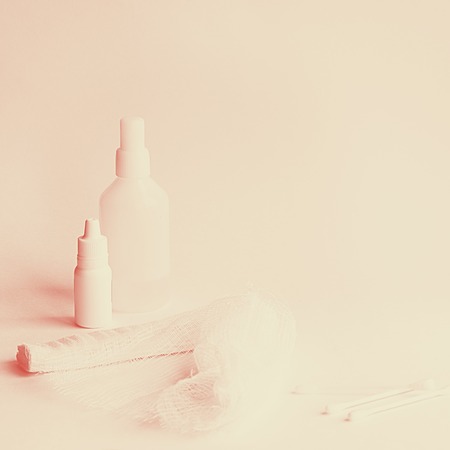 two white medicine bottles big and little, roller bandage and three cotton buds on the white background Square shot with copy space Coral duotoneの写真素材