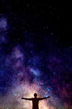 dark silhouette of man with opened hands under beautiful bright night sky with Milky way. Space concept for postcard, wallpaper or design, Vertical with copy space background for textの写真素材