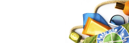 Orange Mock up Bottle of sun screen blue sunglasses and beach wrap in bright fabric bag on white blank background with copy space for design. Holiday flat lay. Long horizontal bannerの写真素材