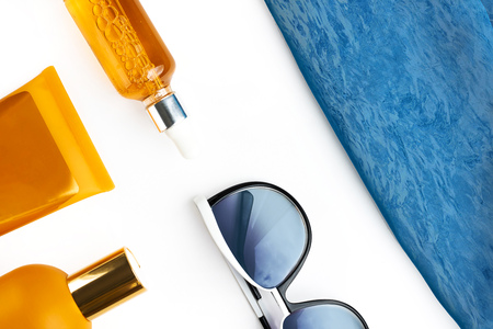 Orange mock up bottles of sun screen and sunglasses, bright contrast blue beach wrap on horizontal blank white background. Holiday flat layの写真素材