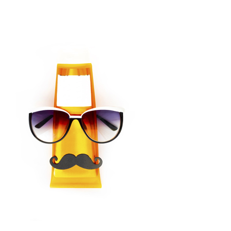 Orange bottle of sun screen with black moustache and dark blue sunglasses put like human face on horizontal blank white background with copy space. Holiday contemporary flat lay.の写真素材
