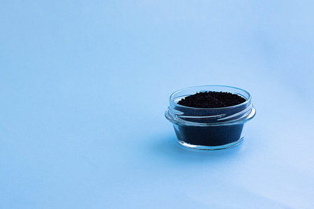 Dry raw sweet black basil seeds, other name tukhmaria or falooda or sabja in glass bowl on blue...