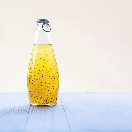 Colorful citrus refreshing summer drink with basil seeds in bottle with blue metal cap on light background. Square with copy space Healthy beverage, superfood, detox, veganの写真素材