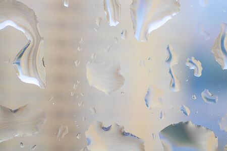 abstract water drops on glass. defocused ogrange and blue background. Horizontal. Rainy day View through the windowの写真素材