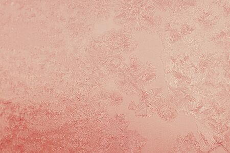 Ice patterns on winter glass of window, with the light seen through it. Light coral duotone. Selective focus. Creative background about winter, cold, christmas time. Horizontalの写真素材