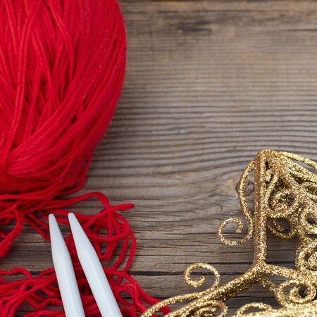 knitting sticks red yarn and yellow christmas decoration on old textured wooden background. Square with copy space. Clew ball with accessories, winter gift, present for handworkの写真素材