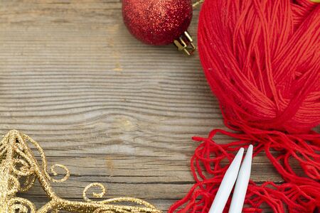 knitting sticks red yarn and christmas decoration on old textured wooden background. Horizontal with copy space. Clew ball with accessories, winter gift, present for handworkの写真素材
