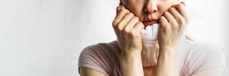 Lower part part of woman face with Red bubbles of virus herpes on her lips she tries to hide it under white knitted neckwarmer, Zoster, Cold, Medicine, Treatment. Horizontal copy space, winter diseaseの写真素材