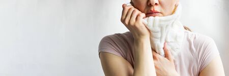 Lower part part of woman face with Red bubbles of virus herpes on her lips she tries to hide it under white knitted neckwarmer, Zoster, Cold, Medicine, Treatment. Horizontal copy space, winter diseaseの写真素材