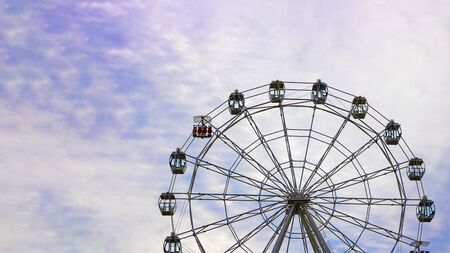Empty Observation wheel on the background of blue sky with white clouds. Horizontal with copy space for text of design about theme park and amusement. Day time. Summerの写真素材