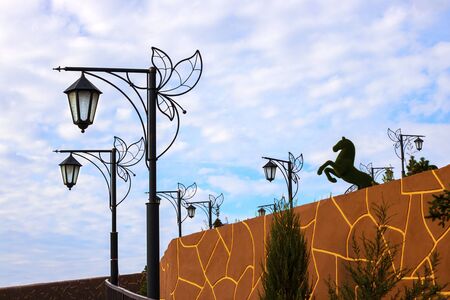 street beutiful vintage lamps aligned with beautiful blue sky with white clouds on background and horse figure shilouette seen from far away. Horizontal with copy space Urban architecture, city designの写真素材