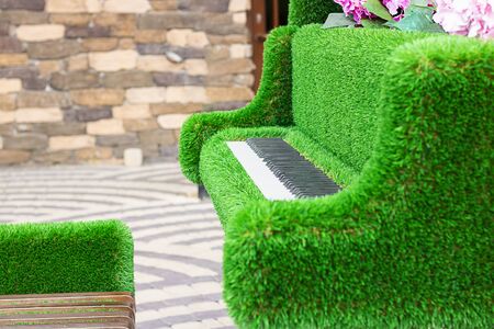 Green sculpture of grand piano with real white and black keyboard and special stool made from artificial grass. Urban design, city architecture, park decoration, open air music. Horizonta copy spaceの写真素材