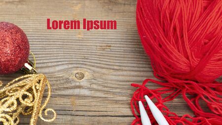 knitting sticks red yarn and christmas decoration on old textured wooden background. Clew ball with accessories, winter gift, present for handwork. Horizontal banner with text on copy space.の写真素材