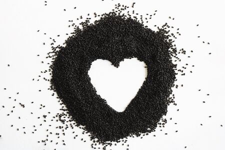 Dry sweet basil seed. Handful on white empty background heart shape. Healthy and super food. Horizontal. Isolate.の写真素材