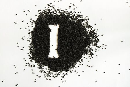 Handful of sweet basil black seeds, letter I uppercase of English alphabet on white background. Black and white. Lettering. Typography. Horizontal. Healthy and super food.の写真素材