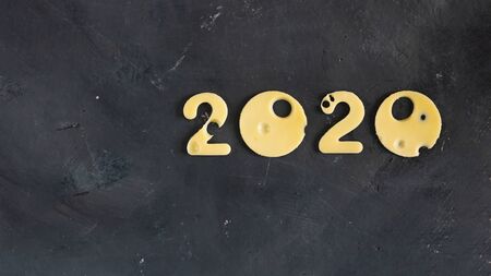 Figures 2020 made of cheese with holes, on a black contrast chalk board background, symbol of proper nutrition and education. Horizontal frame. Christmas and New year conceptの写真素材