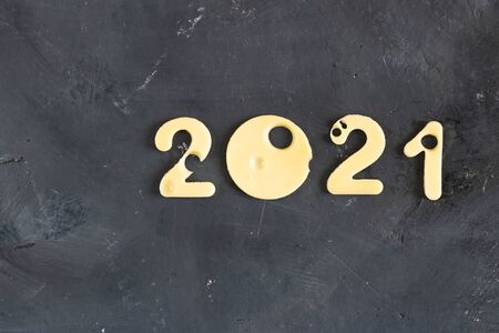Figures 2021 made of cheese with holes, on a black contrast chalk board background, symbol of proper nutrition and education. Horizontal frame. Christmas and New year conceptの写真素材