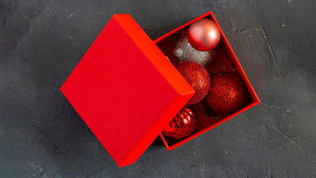 Christmas decoration balls in opened red gift box on black ckalk board backgroud with copy space....