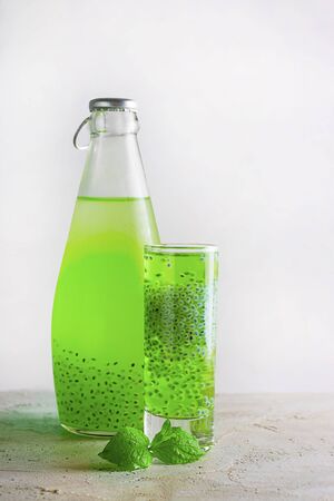 Shot and bottle with green basil seeds drink with fresh mint leave on grey textured background with shadow. Vertical, copy space. Minimal concept about healthy beverage, super food. Falooda, sabjaの写真素材
